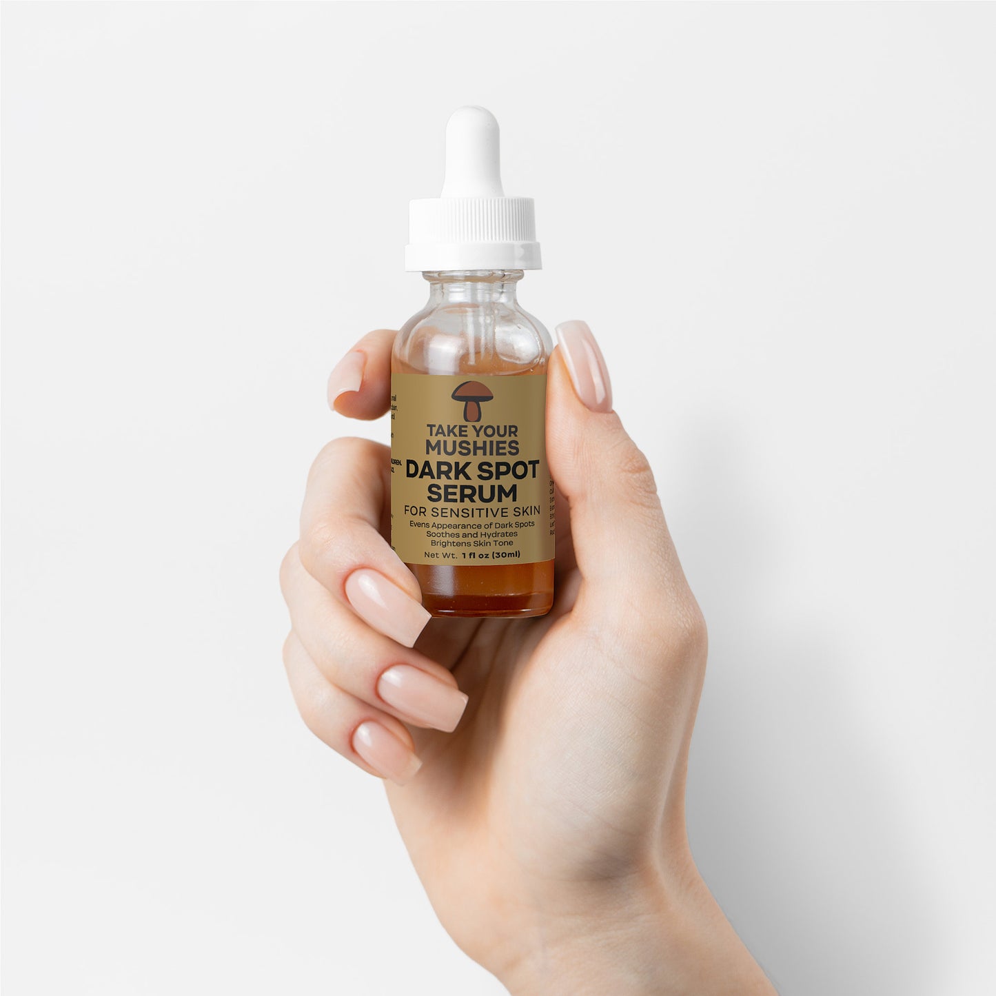 Hand holding a bottle of dark spot serum with a white background. mushrooms even appearance takeyourmushies