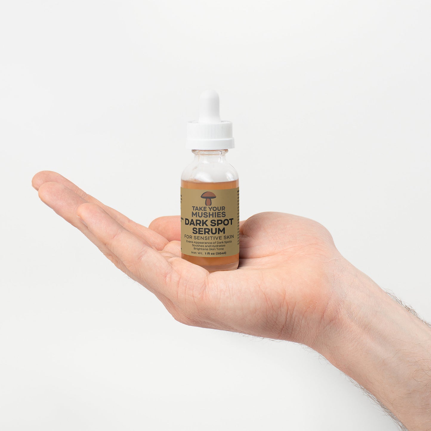 Hand holding a bottle of dark spot serum with a plain background. Takeyourmushies dark spot serum all natural mushroom serum