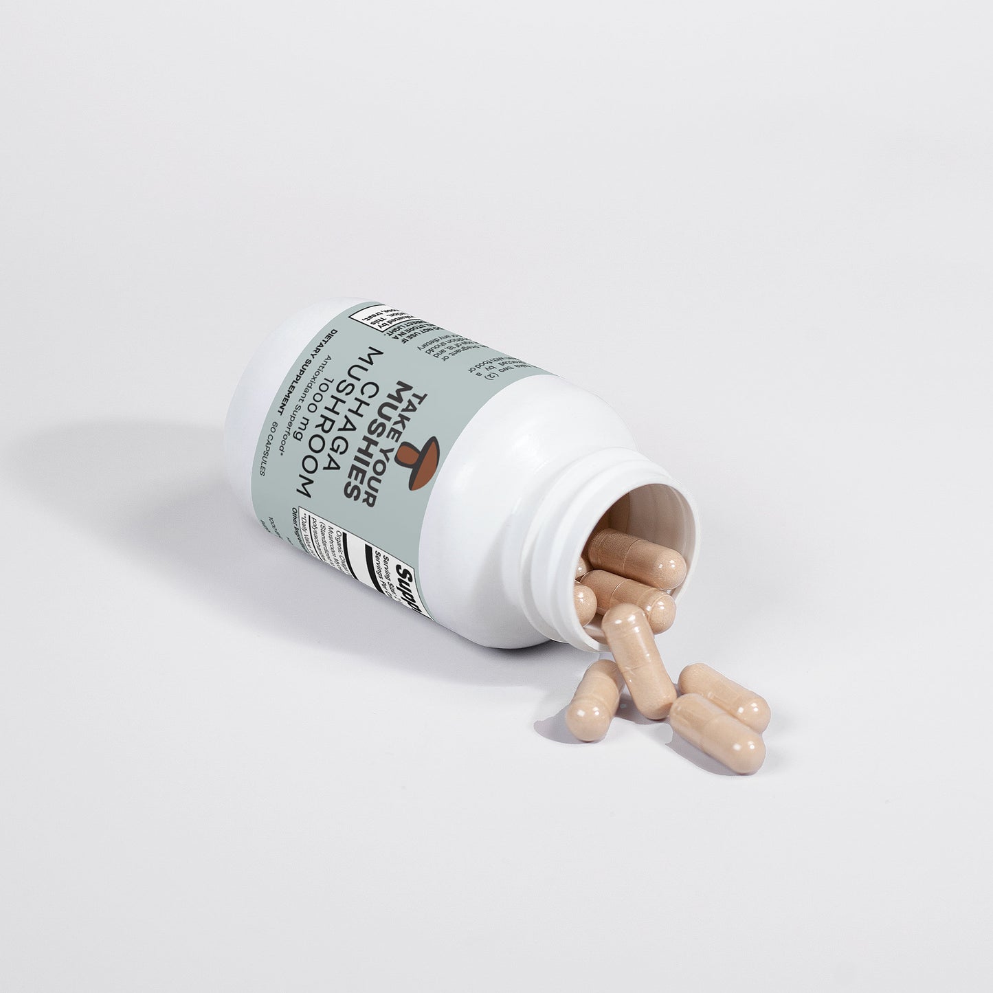 Bottle of chaga mushroom daily capsules spilling out on a white background