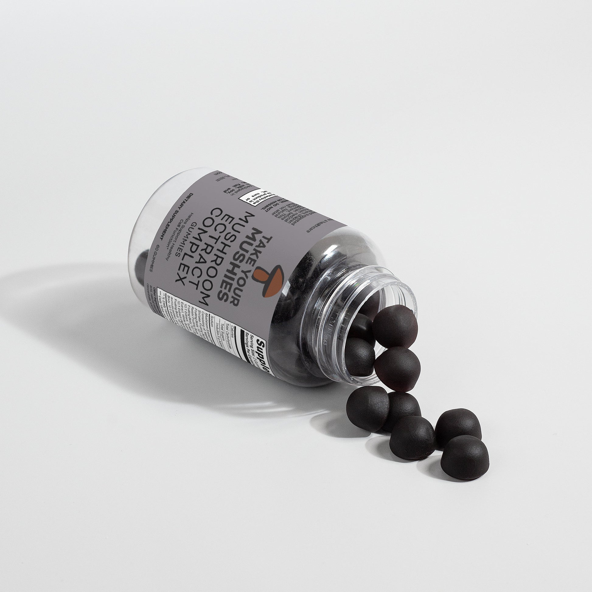 Bottle of supplements with black capsules spilling out on a light gray background